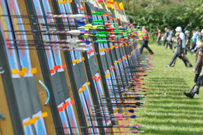 An Oxford Archers tournament with many targets bristling with arrows as archers approach to score